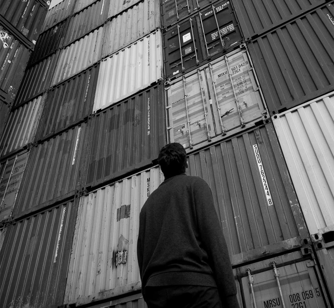 exporting and importing, a person standing in front of a stack of freight containers